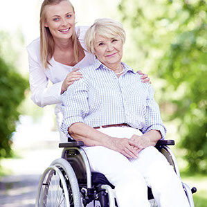 Junge Frau ist freundlich zu Seniorin im Rollstuhl